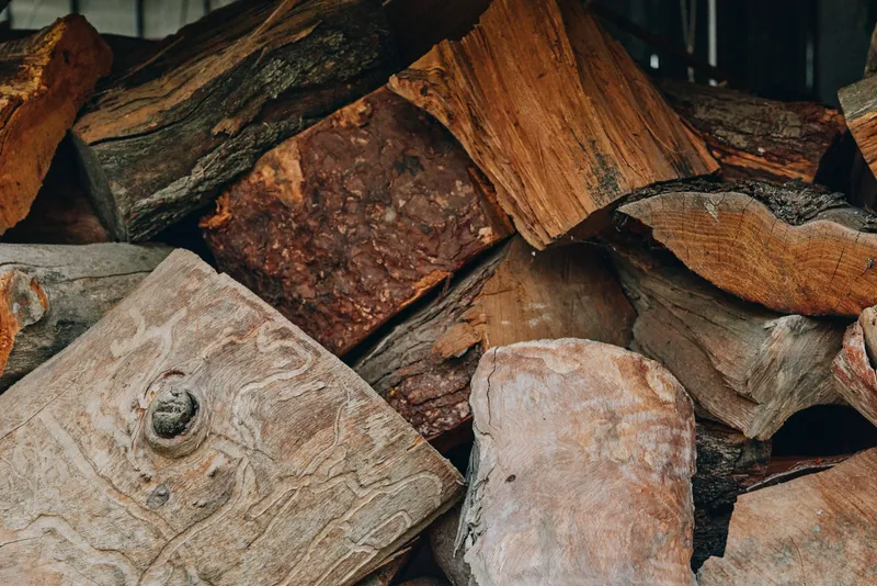 Firewood, logs, woodpile, chopped wood, rustic, texture, fireplace, cabin. Close-up of stacked seasoned firewood with rough bark and warm brown tones for cozy cabin heating and winter lifestyle.