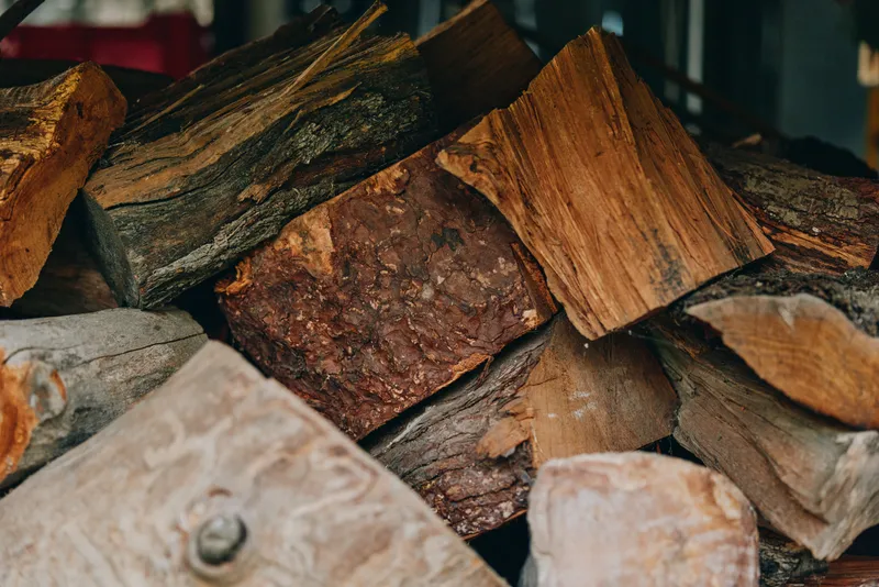 Firewood logs and chopped wood stacked in a rustic woodpile, closeup texture of timber and fireplace wood, fuelwood prepared for winter cabin heating and cozy campfire.