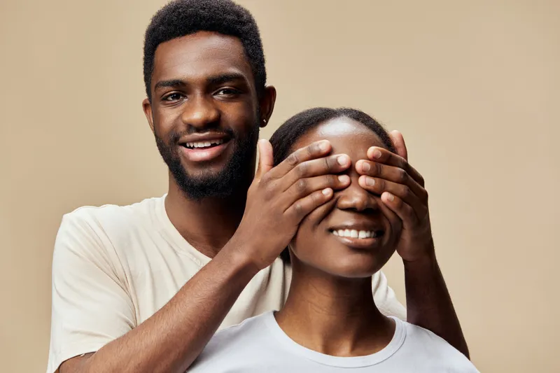 Happy couple playfully covering each other s eyes, showcasing love and connection against a neutral background, perfect for romantic themes and relationships