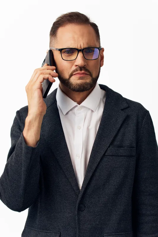A focused business professional man speaks on a smartphone, projecting concentration, resolve, and focus against an isolated colored background, conveying corporate communication, leadership, and