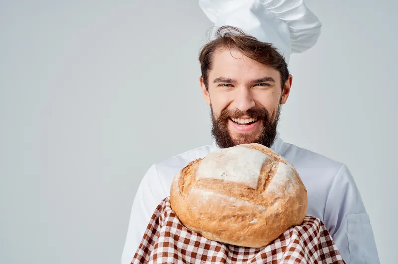Бородатый мужчина-шеф-повар на кухне, работа на светлом фоне