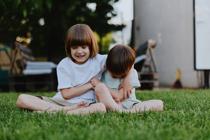 Happy children playing together in the green grass, enjoying a sunny day in the garden with smiles and laughter, creating lasting memories of childhood joy.