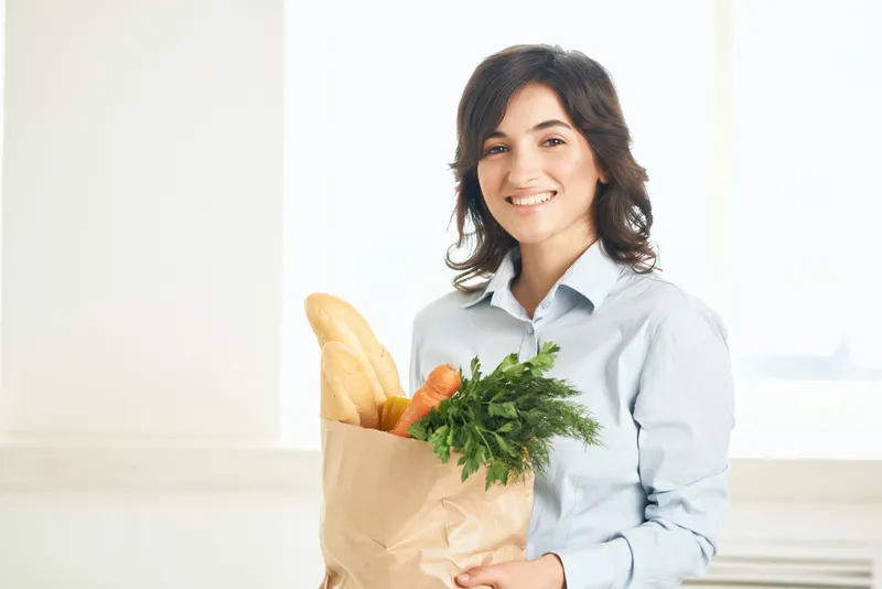 Жизнерадостная женщина с пакетом продуктов, здоровое питание, овощи, домохозяйка