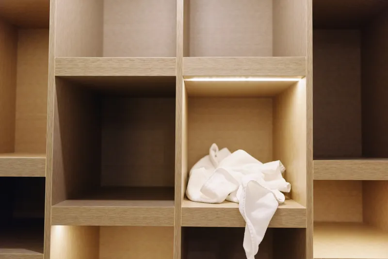 Storage shelves with cubbies and a crumpled tissue in one compartment, warm wood tones and minimalist design emphasizing simple organization and quiet interior.