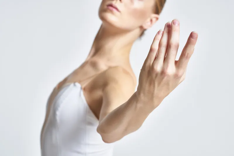 Светловолосая женщина в белом платье жестом останавливает зрителя