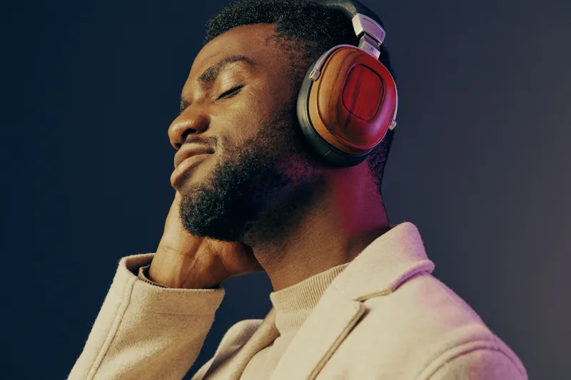 Man enjoying music with stylish headphones, displaying a relaxed emotion in a modern setting with a gradient background that emphasizes serenity and focus