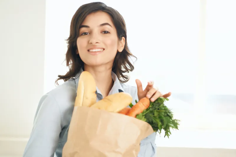 Милый образ брюнетки с пакетом продуктов, полным овощей, здоровое питание и образ жизни