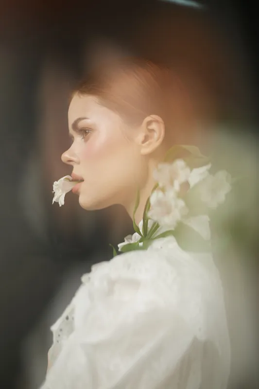 Delicate portrait of a young woman in a white blouse with flowers, embodying beauty and tranquility in soft pastel tones, perfect for spring themed concepts