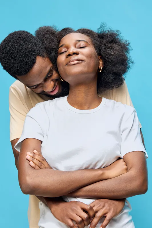 Joyful couple embracing against a vibrant blue background, showcasing love and connection, perfect for depicting intimacy and emotional bonds in photography