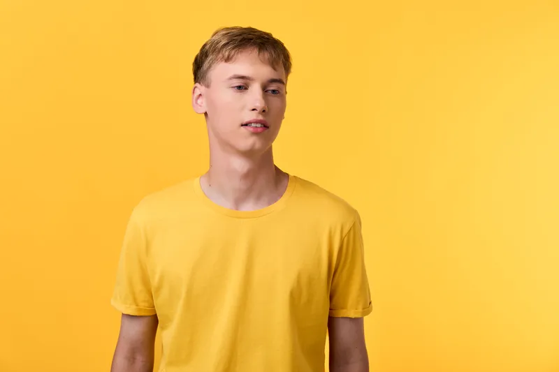 Yellow man in a casual studio shot, minimal composition and bold color harmony, presenting a relaxed mood and modern fashion vibe