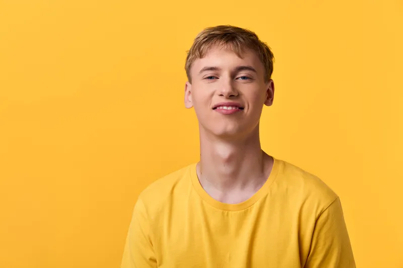 Smiling man in a bright yellow shirt against a vivid yellow backdrop, casual lifestyle shot capturing positive energy and simple studio setup for marketing and social media use