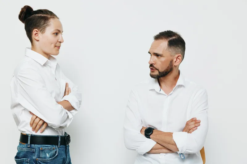 A professional man and colleague engage in a focused discussion against an isolated white background, projecting confidence, authority, and clear business mindset in a studio setting.