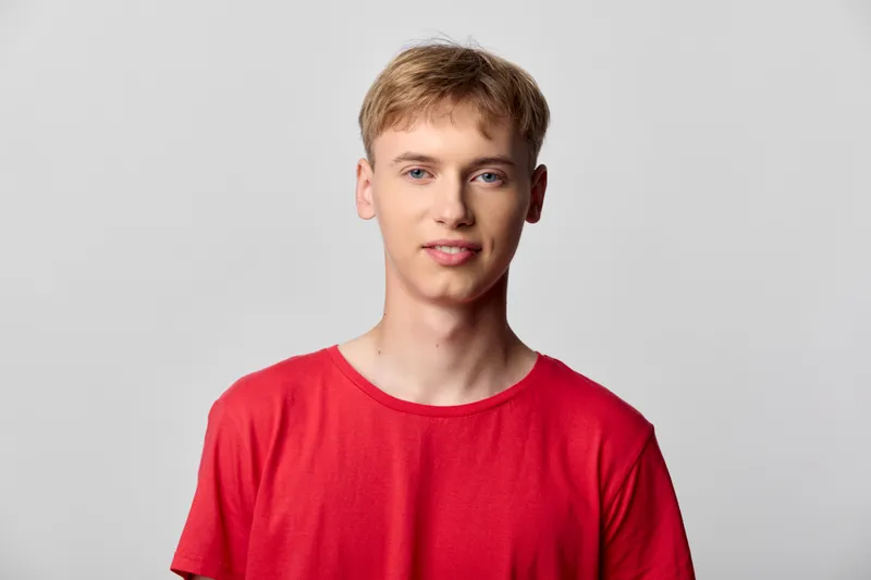 Male model wearing a red shirt in a clean studio, bright lighting and minimal styling, approachable look for casual fashion, lifestyle, or ecommerce stock photography.