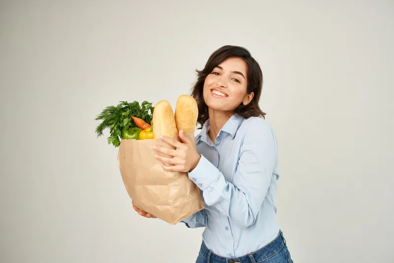 Симпатичная брюнетка с пакетом органических продуктов, овощей и товаров для здоровья