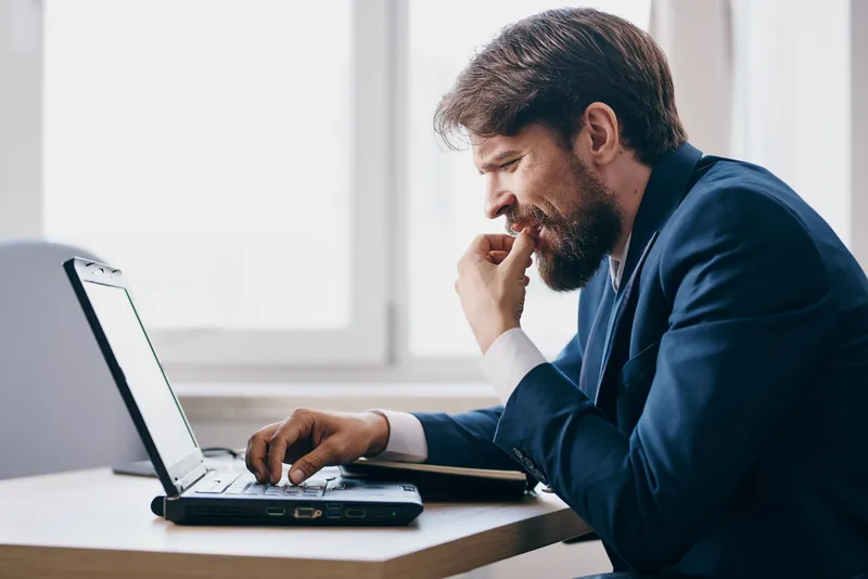 Менеджер работает за ноутбуком в офисе, испытывая эмоции, связанные с интернетом и профессиональной деятельностью