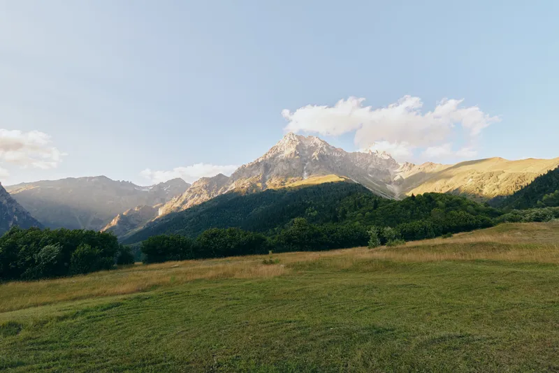 Tranquil meadow with rolling hills and distant mountains under a clear blue sky, a calm outdoor landscape ideal for nature lovers and travel storytelling and tranquil mood.