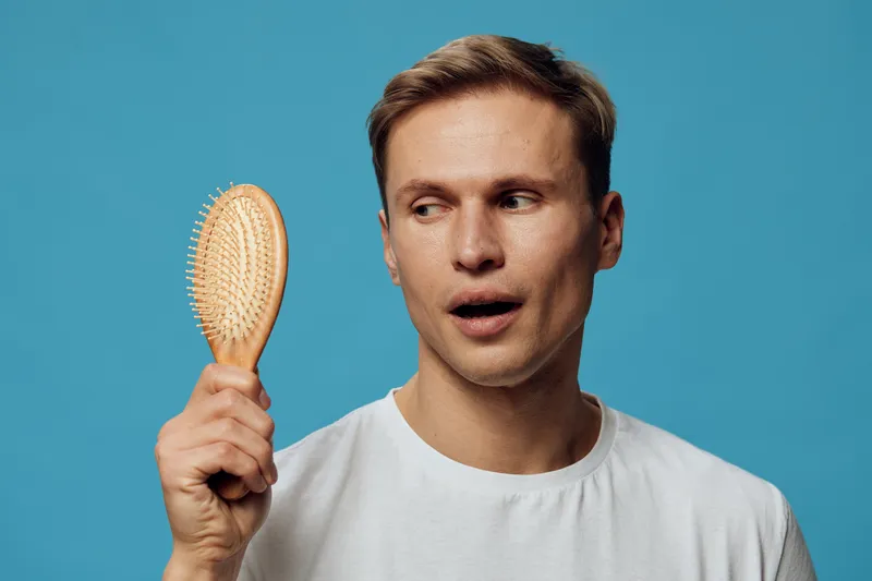 surprised man holding wooden hairbrush white t shirt blue background personal care grooming hygiene concept