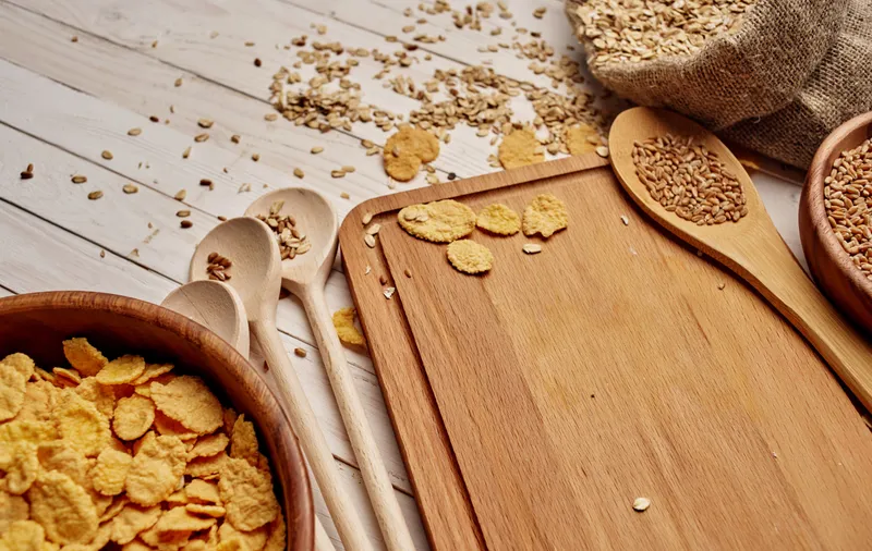 Крупы в пакете, кукурузные хлопья, деревянная доска, ложка, еда