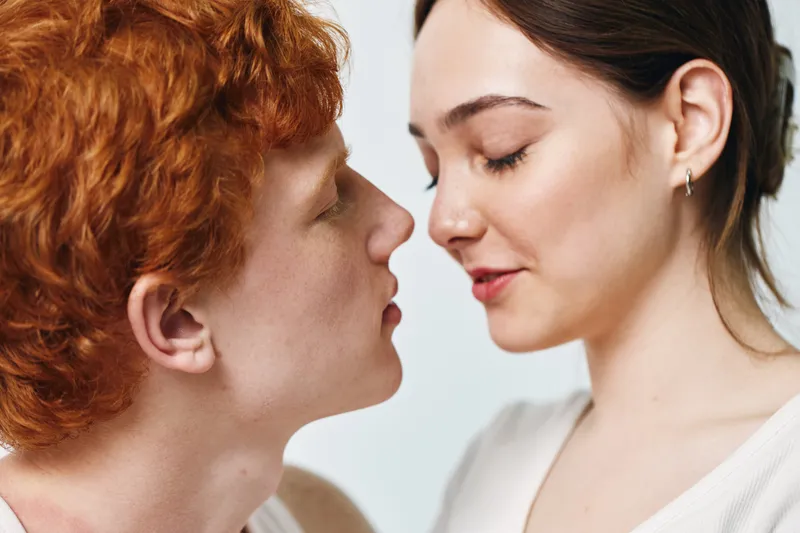 Couple with closed eyes, closeup portrait of man and woman in tender moment. Young lovers with affectionate expression and gentle intimacy on white background.