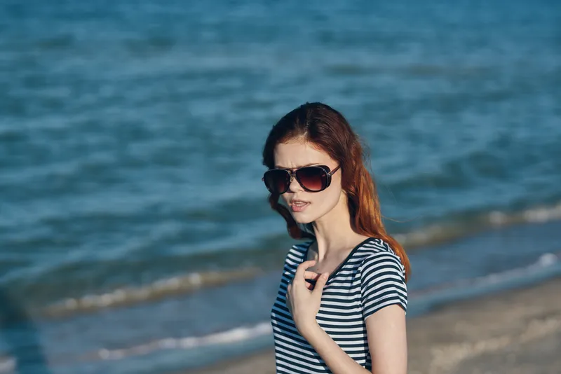 Женщина в футболке на пляже в горах у моря