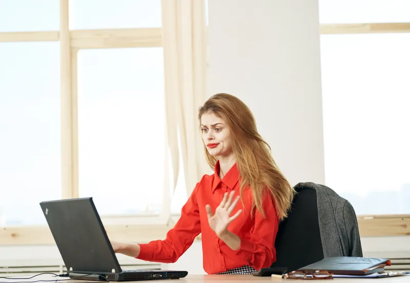 Деловая женщина работает за столом в офисе с ноутбуком, занимаясь менеджментом и коммуникацией