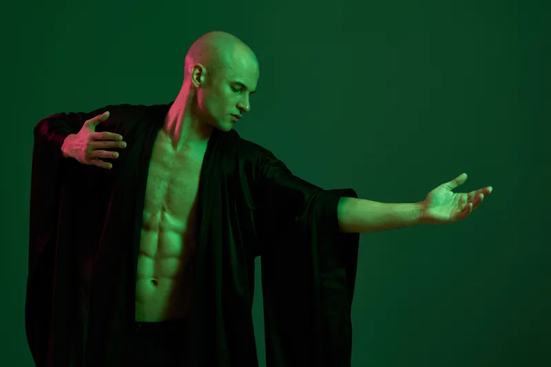 Dynamic man in flowy garment elegantly posing, showcasing his graceful movements. The image features rich green tones. Concept: expression of art.