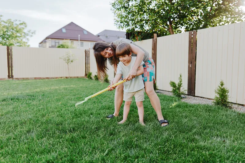 Happy woman playing with a child in the backyard, enjoying a sunny day together while creating joyful memories filled with laughter and love.