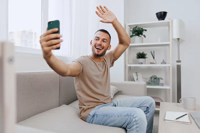 A smiling man taking a phone call at home, embracing emotional connection and authentic imperfection, balancing personal and professional life.