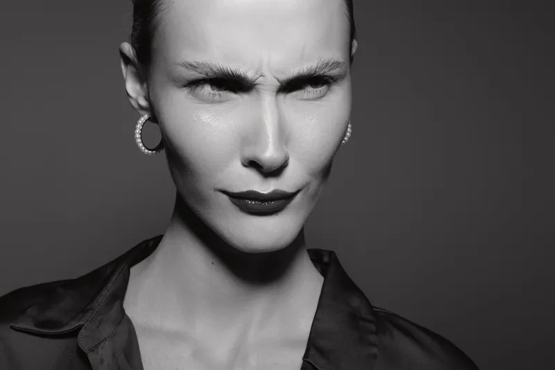Close-up portrait of a serious Caucasian woman with light skin and hoop earrings, furrowing her brow and pursing lips. Concept of skepticism and doubt in monochrome.