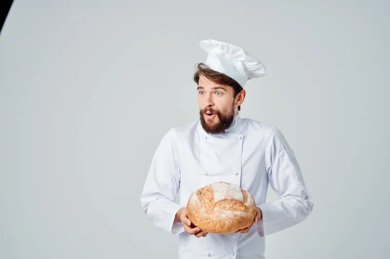 Повар на кухне, работа с хлебобулочными изделиями на светлом фоне