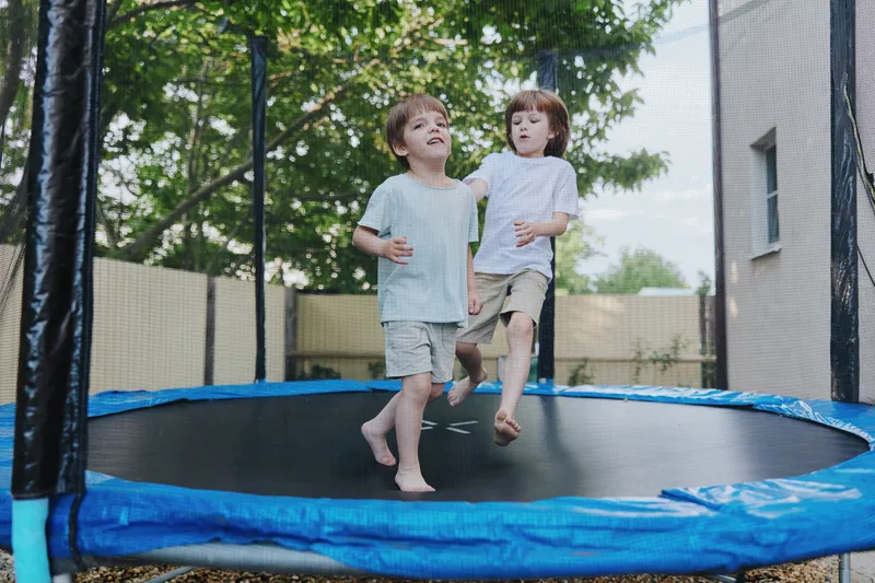 Happy children jumping on a trampoline, enjoying a sunny day outdoors, with laughter and joy in the air. Perfect for family and childhood themes.