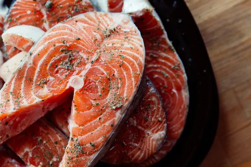 Маринованная красная рыба на тарелке, приготовление морепродуктов, деликатес