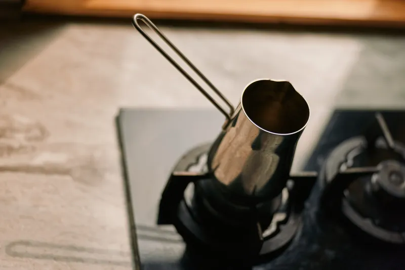 coffee pot stovetop metal copper vessel on gas burner in kitchen for brewing traditional coffee morning ritual