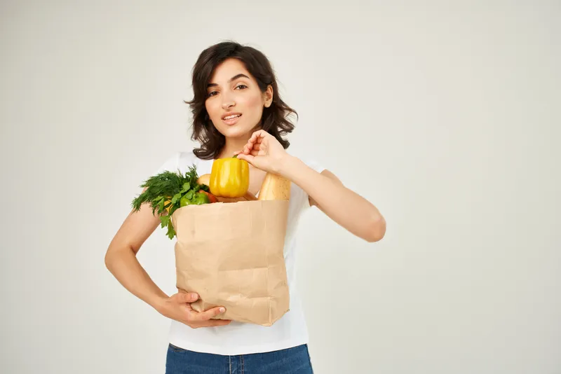Брюнетка с пакетом продуктов в супермаркете службы доставки