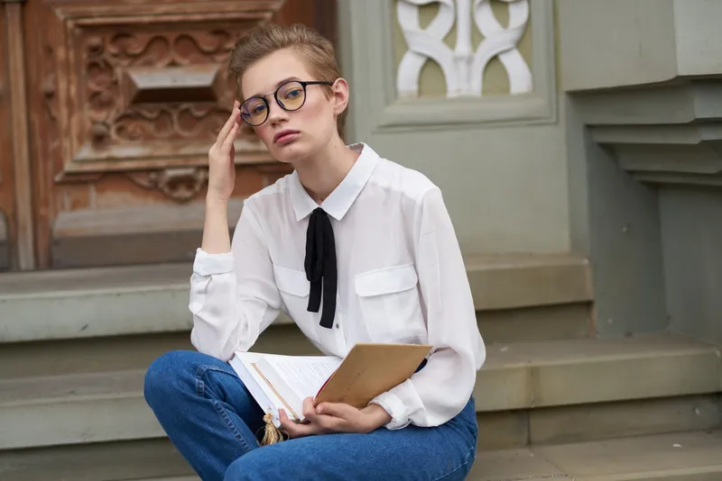 Студент в очках гуляет по городу с книгой, посвящая время образованию