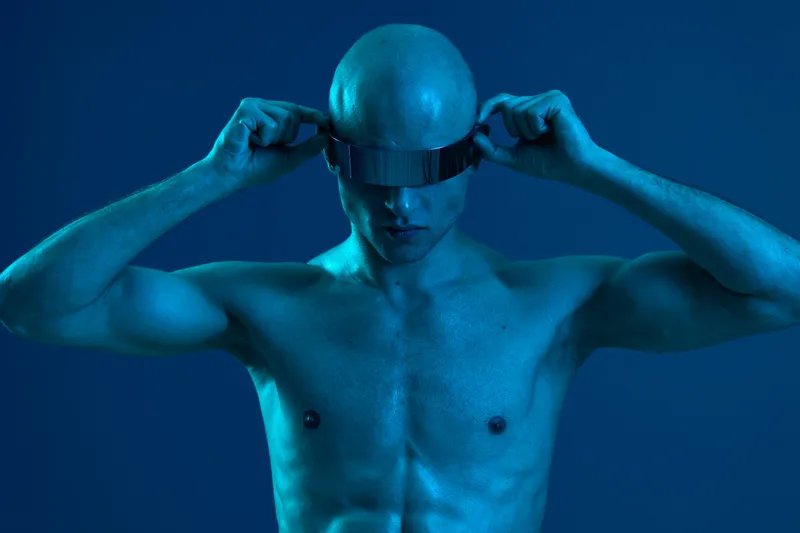 A striking image of a man adjusting futuristic goggles, showcasing a blue monochrome palette, exuding a bold and tech-savvy vibe.