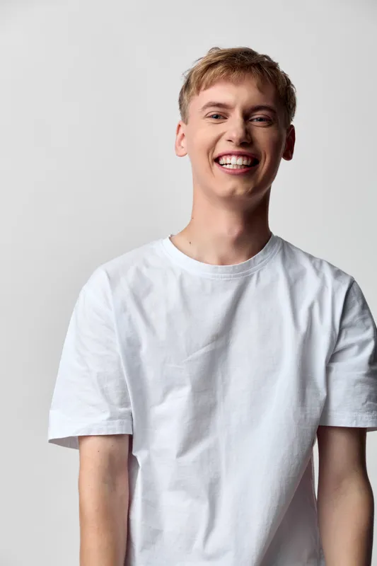 Smiling man in a tshirt captured in a casual studio setting, showcasing a bright, friendly expression suitable for lifestyle, fashion and positive branding photography
