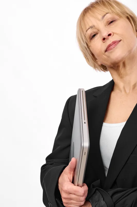 Senior business woman in black suit holds a tablet and document folder, smiling at camera on clean white background, corporate portrait