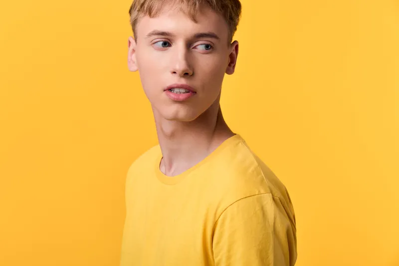 Man in a yellow shirt in a bright studio setting, close up of casual fashion, confident expression and youthful look, clean lighting for commercial stock use