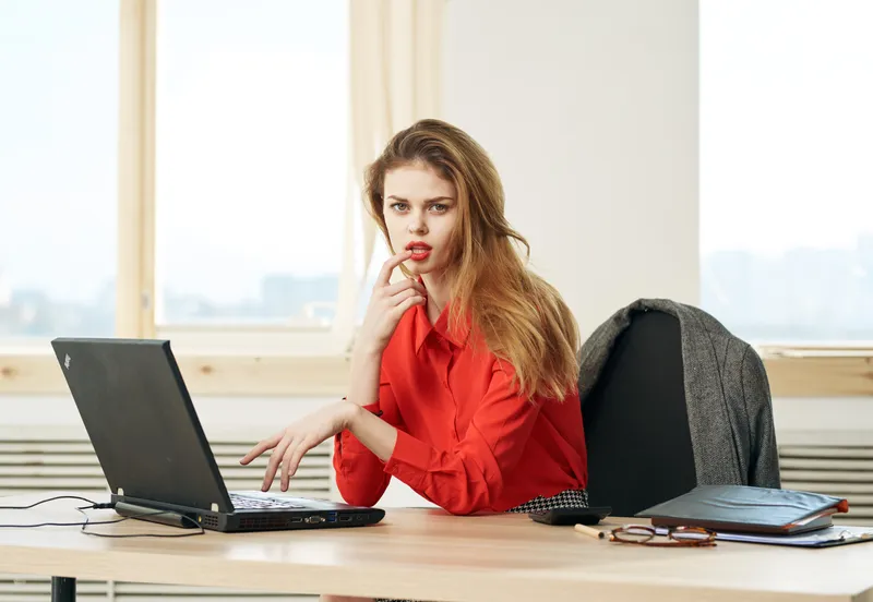 Деловая женщина работает за столом в офисе за ноутбуком в роли секретаря