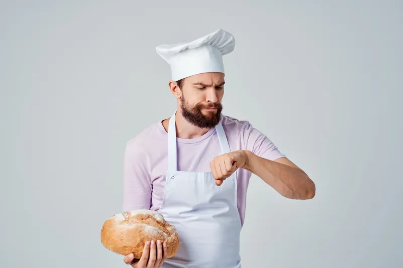 Бородатый мужчина в фартуке готовит еду на кухне ресторана