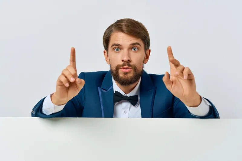 Веселый мужчина в костюме держит белый постер для мокапа, скидка, реклама, белый фон