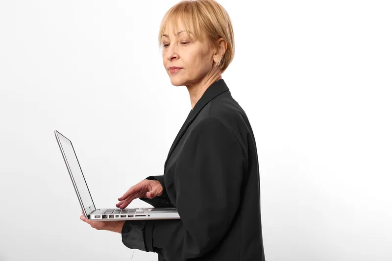 Woman using laptop for business typing, professional corporate manager working, focused face, studio side view, isolated on white background, office workflow