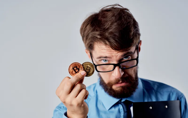 Мужчина, успешный финансист, держит в руках криптовалюту Bitcoin, технологии