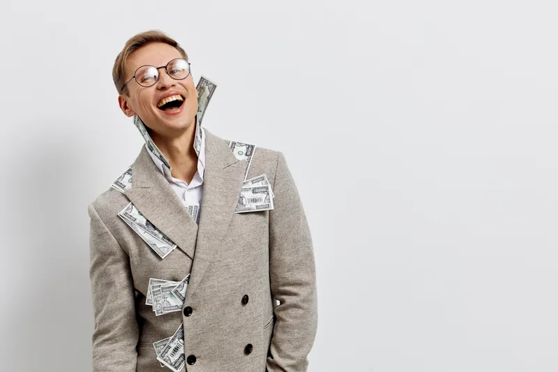 Happy professional woman laughing joyfully wearing a stylish plaid blazer with money bills attached, expression of success and confidence, isolated on plain white background, studio portrait. Business