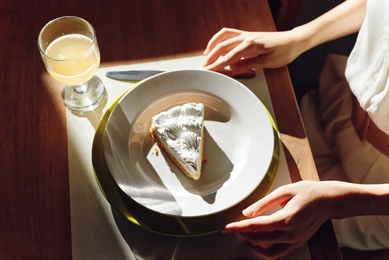 Элегантная женщина наслаждается романтическим ужином дома, смакуя вкусную домашнюю еду с блаженной улыбкой