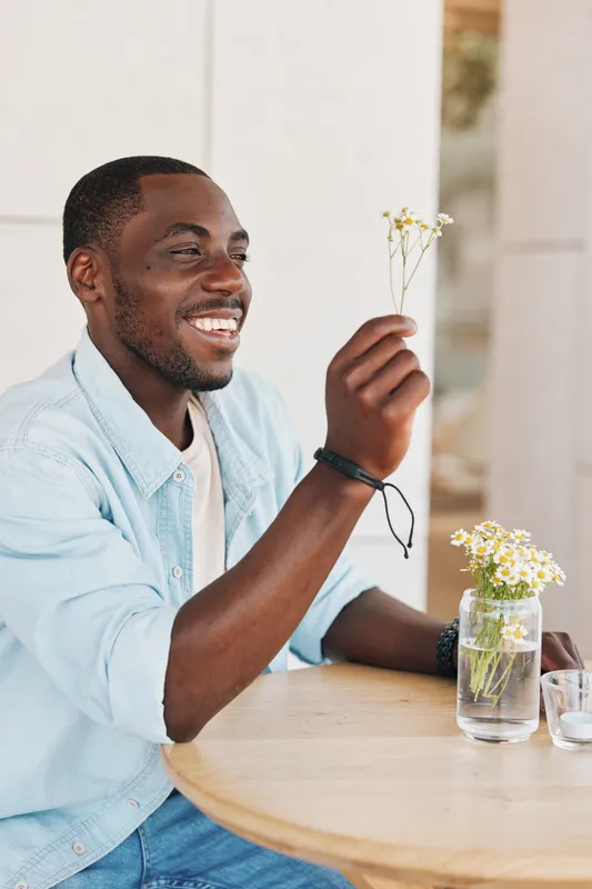 Молодой мужчина с привлекательной улыбкой смотрит в камеру, держа телефон