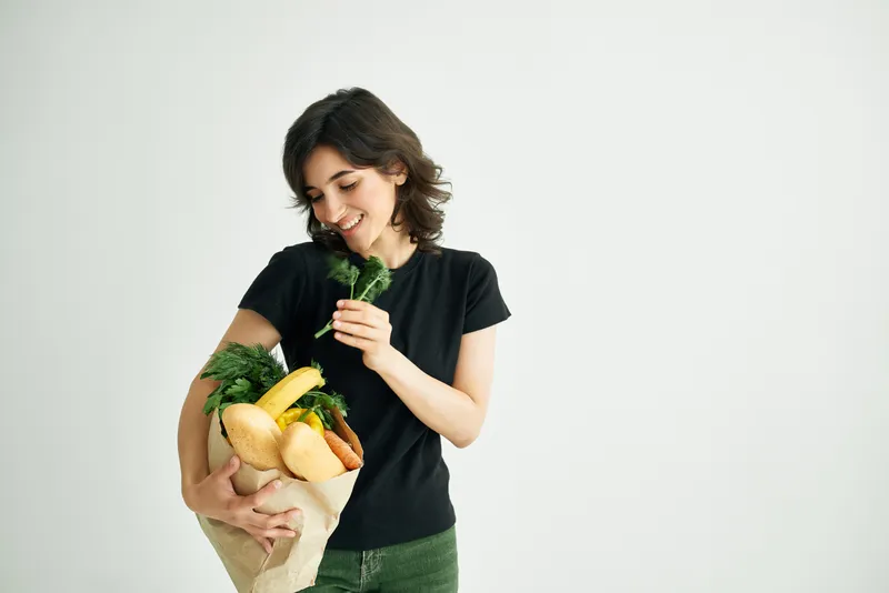 Весёлая женщина с пакетом продуктов во время шопинга