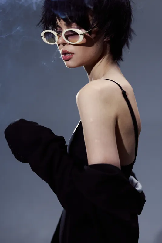 Stylish woman with short hair wearing sunglasses and a black outfit in a modern minimalistic setting