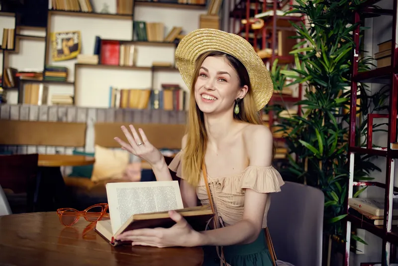 Симпатичная женщина с книгой в руках в кафе, общается